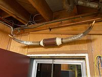 Full view of the horn wall ornament mounted on a wooden wall, showing the long curved horns and central plaque.