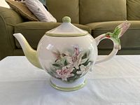Front view of teapot showing floral design and hummingbird handle
