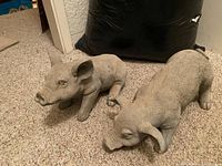 Two pig statues on carpet, overview of both figures