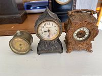 Three antique clocks displayed side by side showing size, design and condition.