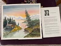 Watercolour painting showing landscape with cabin, trees, water and mountains, signed M F Halsey, next to informational sheet about the artist.