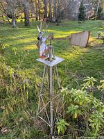 Full view of vintage outdoor metal wind turbine weather vane in a grassy backyard setting showing base, tower and turbine with tail vane.