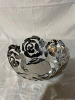 Front view of polished stainless steel bowl with openwork rose petal design showing entire shape and detail.