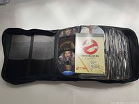 Image showing open carry case with DVDs, featuring 'The Lord of the Rings' and 'Ghostbusters' on top.
