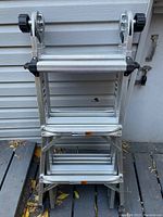 Folded aluminum multipurpose ladder showing step configuration with wide serrated treads and hinge assemblies