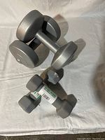 Photo showing one pair of light gray metal dumbbells and one pair of smaller gray neoprene-coated dumbbells.