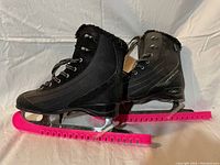 Side view of pair of black ladies figure skates with bright pink blade guards showing overall condition and materials.