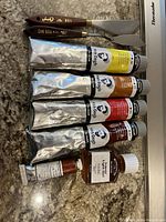Full set of oil paints, mixer scrapers and Liquin Light Gel on marble countertop
