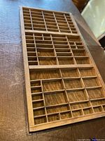 Overhead view of the wooden printer's tray showing the multiple small compartments arranged in rows and columns with various sizes.