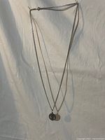 Full view of silver-tone chain necklace with round medallion pendant laid flat on white background.