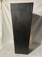 Tall black outdoor planter with vertical grooves, standing upright against white background.