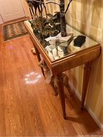 Side view of the mirrored top accent table showing wood finish and mirrored surface with gold trim.