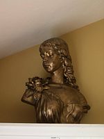 Front angled view showing the bust, with focus on the face and floral detail on the shoulder.