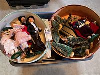 Photo showing two round hat boxes filled with vintage Christmas caroler figurines and miniature trees.