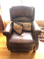 Front view of brown leather recliner with two pillows on seat