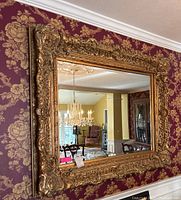 Full view of mirror hanging on wallpapered wall reflecting dining room
