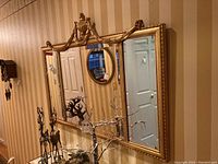 Full view of the large rectangular wall mirror showing the ornate gold frame with garland and urn motifs.