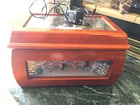 Full view of the wooden Christmas music box with glass top and attached power cord on top.
