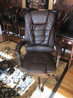 Front angle photo of brown padded rolling office chair showing cushioned seat, armrests, and high backrest upholstery.
