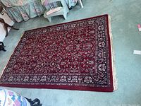 Full view of the red Oriental area rug with floral pattern on a light blue carpet.