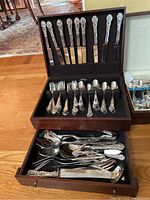 Full view of open wooden storage case showing complete flatware set including knives, forks, spoons and serving utensils.