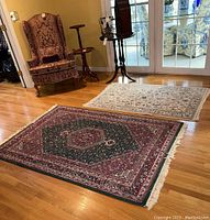 Two rugs laid on hardwood floor with furniture in background