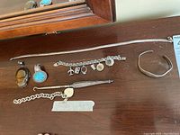 Overview of sterling silver jewelry including bracelets, pendants, charms, and necklace arranged on a wooden surface