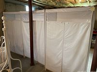 Wide view of three white portable storage closets placed side-by-side in a basement with visible ceiling insulation and concrete floor.