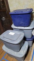 Five plastic storage totes in blue and gray, stacked