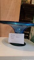 Side view of blue tinted footed glass bowl showing flared rim and base with concentric ring design