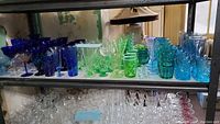 Overall view of metal shelving with assorted blue, green and clear glassware