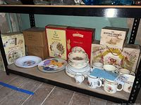 Shelf with boxed and loose children's dishware including Royal Doulton Bunnykins, Wedgwood Peter Rabbit, and children's plates; also boxed Beatrix Potter books