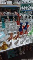 Full view of assorted candlestick pairs on table showing various colors and glass types