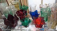 Shelf display of Duncan art glass vases in various colors and ruffled rims.