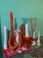 Front view of assorted orange, white, and clear glass items on metal shelf