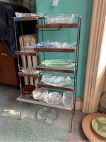 Full view of the vintage metal and wood storage rack with various glass dishes displayed on shelves to demonstrate storage use.