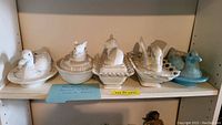 Five milk glass covered dishes with animal lids on a shelf