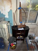 Full view of the sewing cabinet with visible side compartments, multiple drawers open containing sewing supplies and notions. Wooden hoop frame positioned on top.