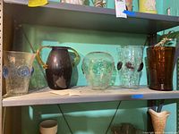 Shelf showing four Blenko glass vases and one brown unknown maker vase arranged in a row.