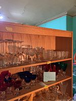 Shelf with various waterford and ralph lauren glassware including colored stemmed glasses and clear glass bowls