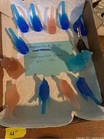 Top view of the Westmoreland frosted glass bird figurines in blue and peach, arranged in a box with a handwritten note about Westmoreland Glass dates.