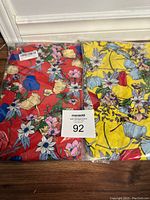 Photo showing two packaged beach dresses by LittleMax in red and yellow floral patterns.