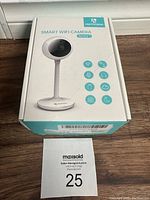 Front view of the HeimVision Sentry 1 Smart WiFi Security Camera in its original box, placed on a surface with MaxSold auction card visible.