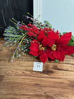 Artificial flower lot on wooden surface, visible red poinsettias, red berries, and purple floral stems.