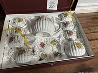Full tea set displayed in original box, showing teapot, cups, creamers, and saucer with floral designs.