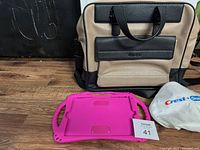 Calvin Klein leather style laptop bag in beige fabric with black textured leather trim, accompanied by a pink iPad case and a white Crest and Oral-B pencil case on wooden floor.