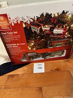 Box front showing train set including locomotive and two cars on track around Christmas tree