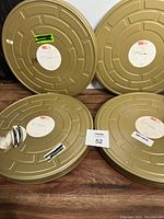 Four gold 35mm movie film canisters stacked and laid side by side on a wooden surface, showing wear and TIFF labels.