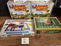 Lot of four board games including two Jumbo Insects kits, Snap Circuits Jr electronic kit, and YukYuks Comedy Game box showing front and top views of each.