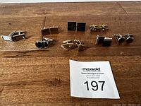 Photo showing all seven pairs of cufflinks arranged on wood surface.